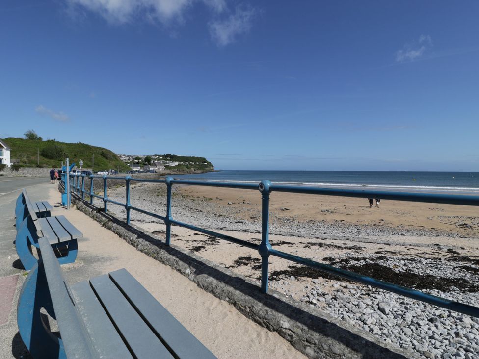 A beach view with benches and railings at Salty Puffin in Benllech