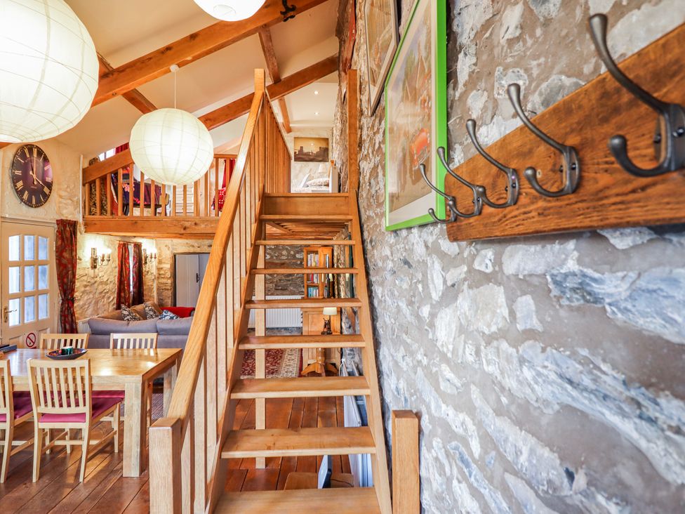 A living room with stairs and dining area at Dovetail Cottage in Llangollen