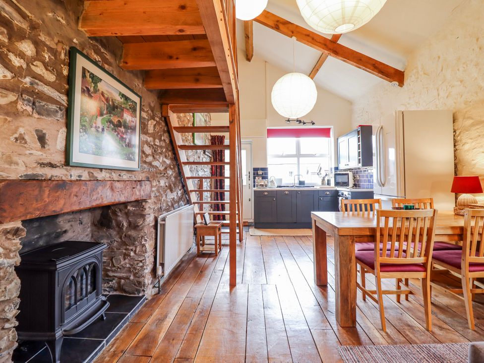 A dining room with a staircase and kitchen at Dovetail Cottage in Llangollen