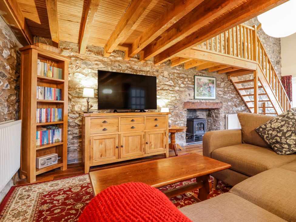 A living room with a television and bookshelf at Dovetail Cottage in Llangollen