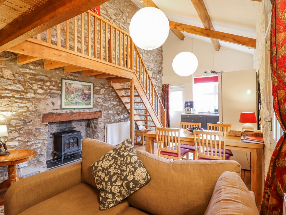 A living room with a staircase and table at Dovetail Cottage in Llangollen