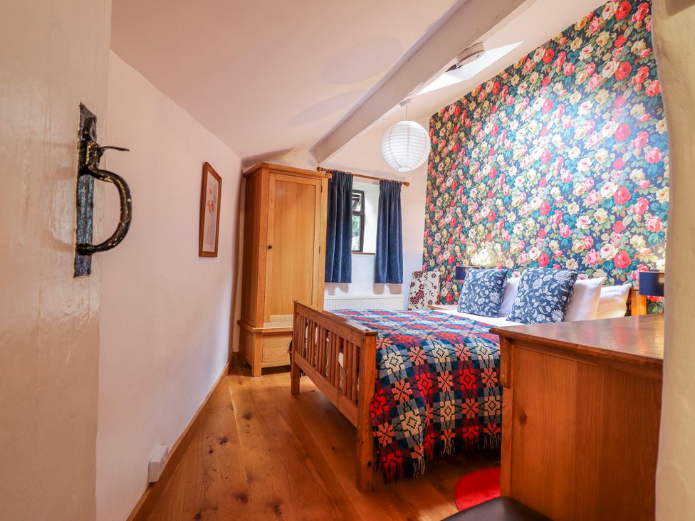 A bedroom with a bed and wardrobe at Dovetail Cottage Llangollen
