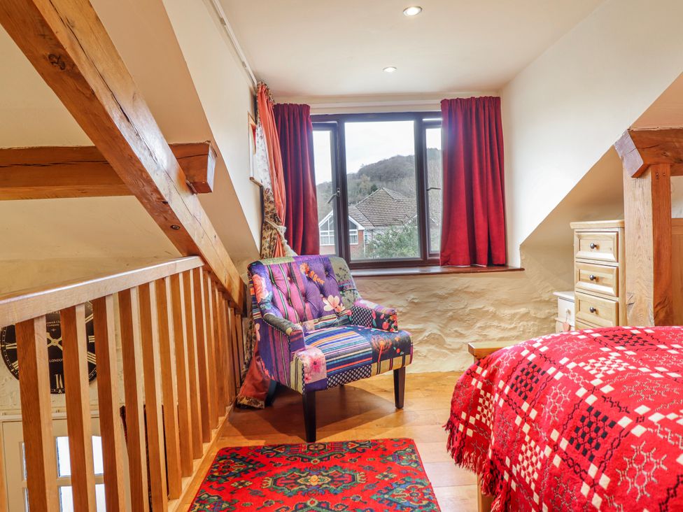 A bedroom with a bed and armchair at Dovetail Cottage Llangollen