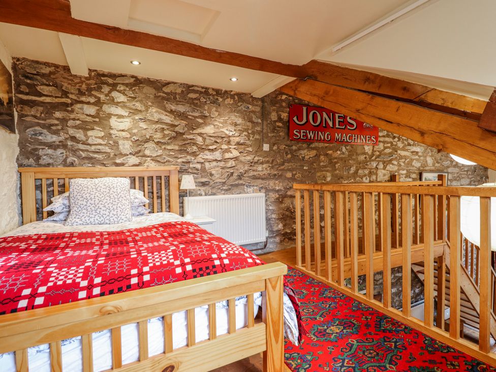 A bedroom with a bed and stone walls at Dovetail Cottage in Llangollen