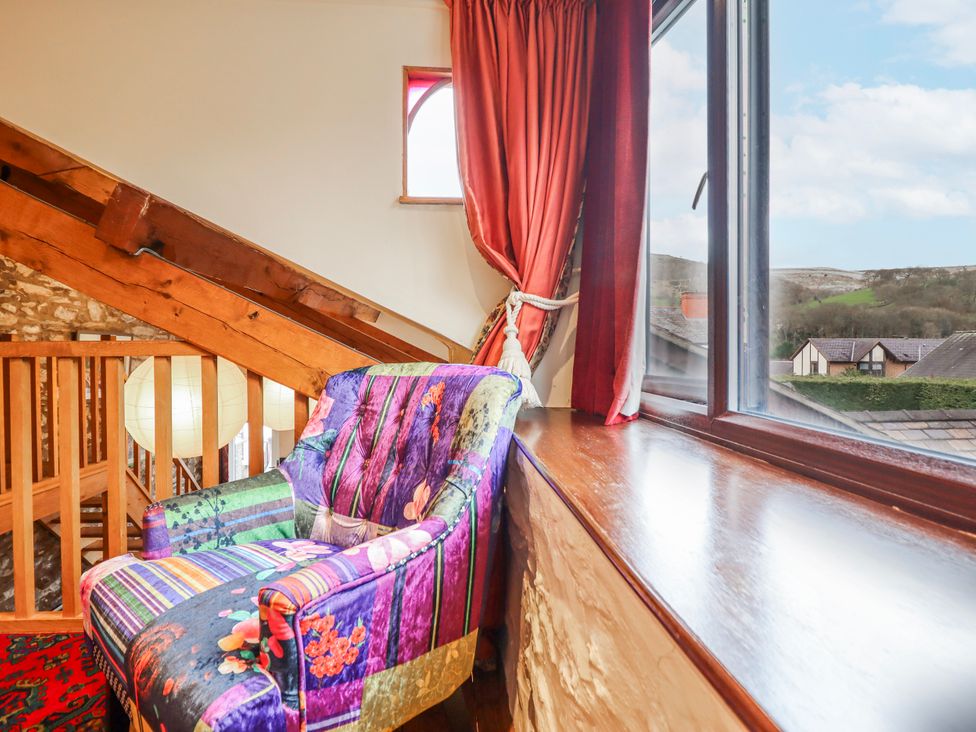 A living room with an armchair and a window at Dovetail Cottage in Llangollen