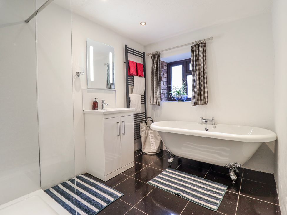 A bathroom with a bathtub and vanity at Dovetail Cottage in Llangollen