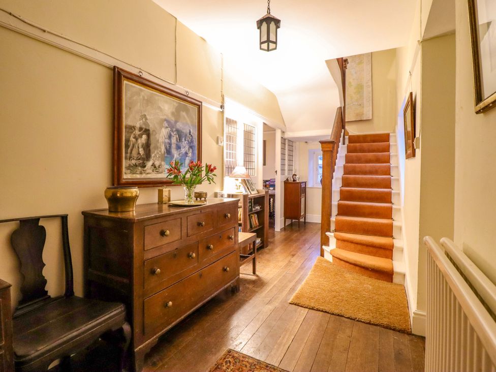 A hallway with a staircase and chest of drawers at Murmur Y Don in Harlech