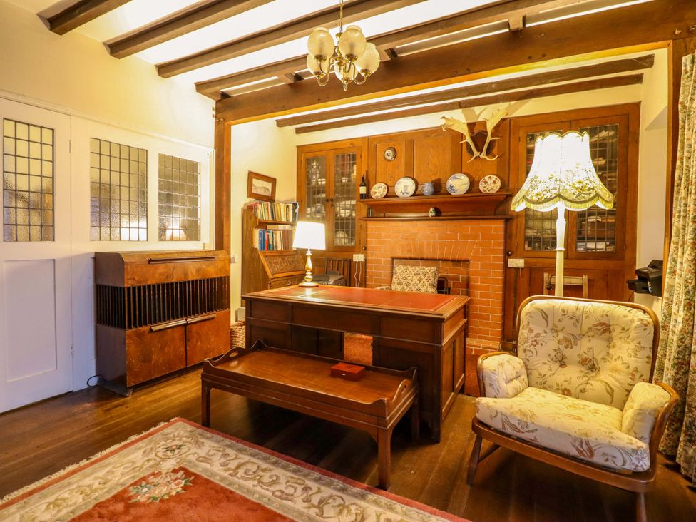 A study with a desk, lamp, and bookshelf at Murmur Y Don in Harlech