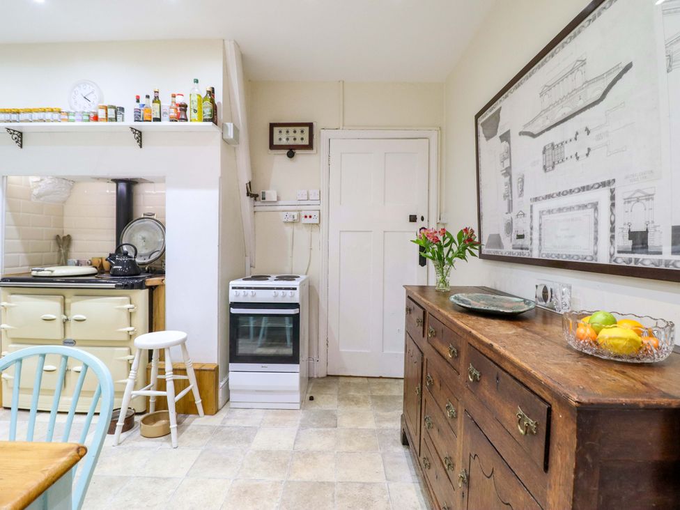 A kitchen with a stove, cabinet, and flowers at Murmur Y Don in Harlech