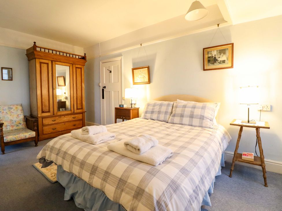 A bedroom with a bed, wardrobe, and armchair at Murmur Y Don in Harlech