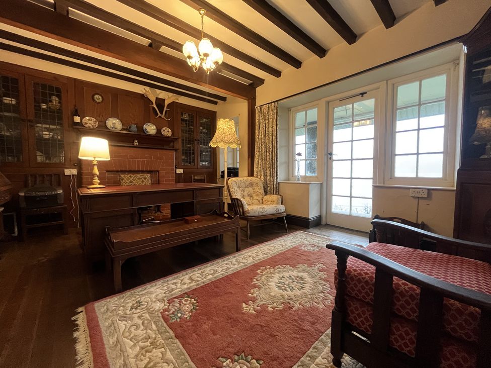 A living room with wooden furniture and a rug at Murmur Y Don in Harlech