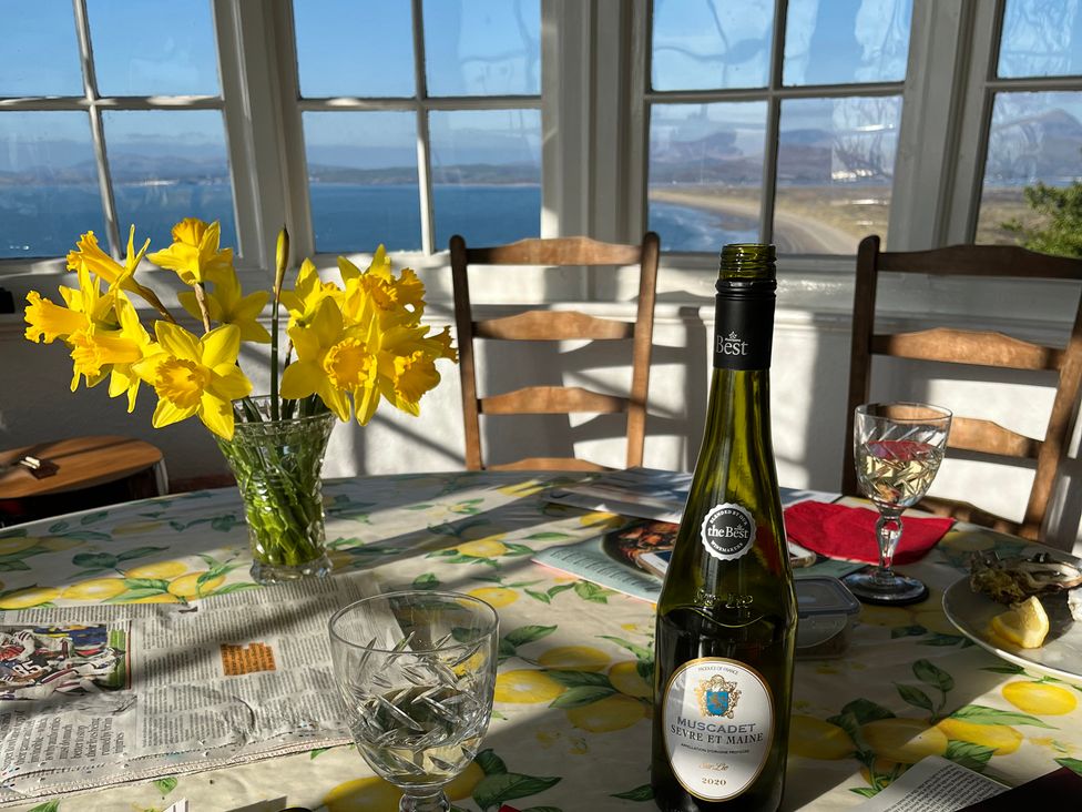 A dining room with flowers and wine on the table at Murmur Y Don in Harlech