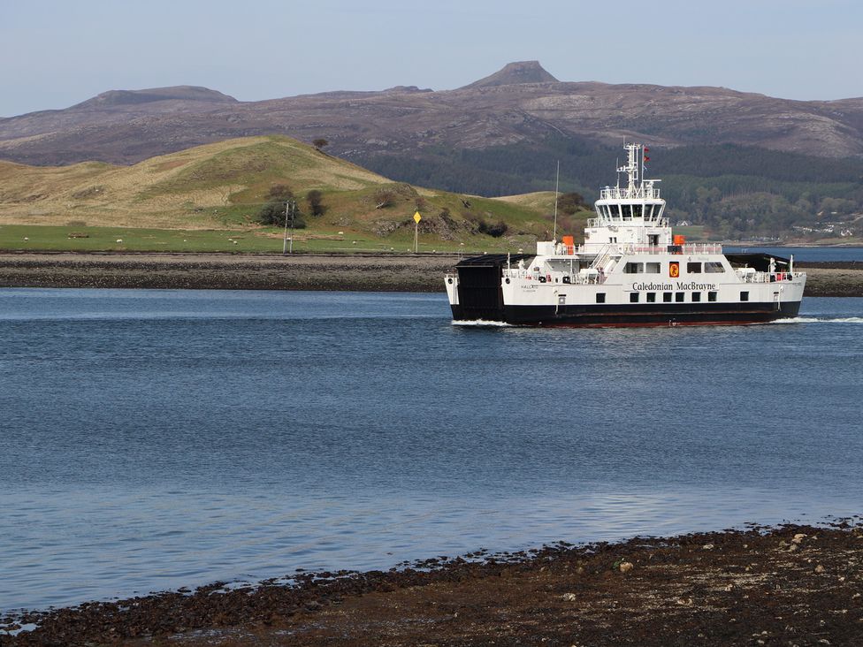 A ferry navigating the water near hills at MacKenzie’s Peak Sconser near Portree