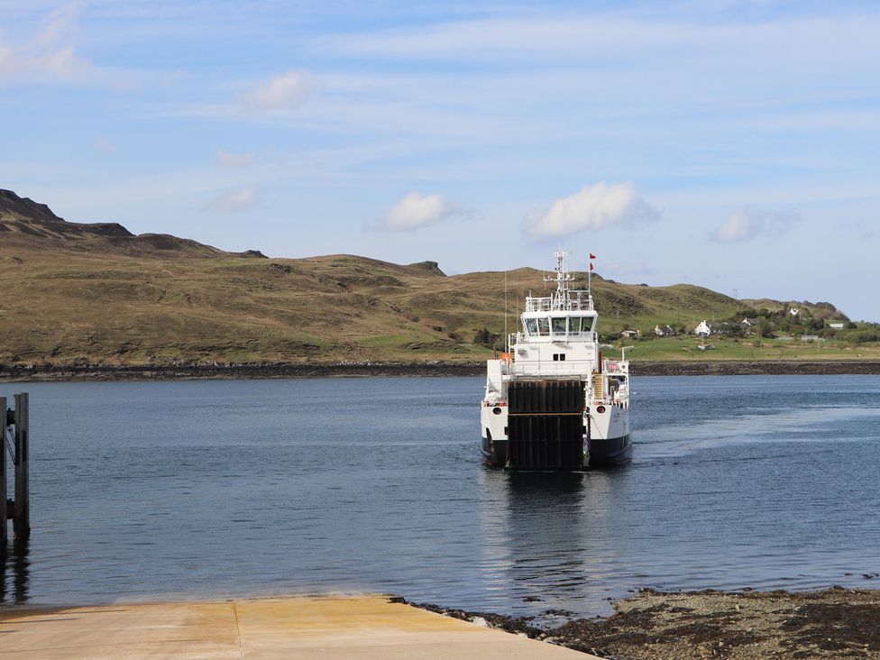 A ferry approaching a pier with hills in the background at MacKenzie’s Peak Sconser near Portree
