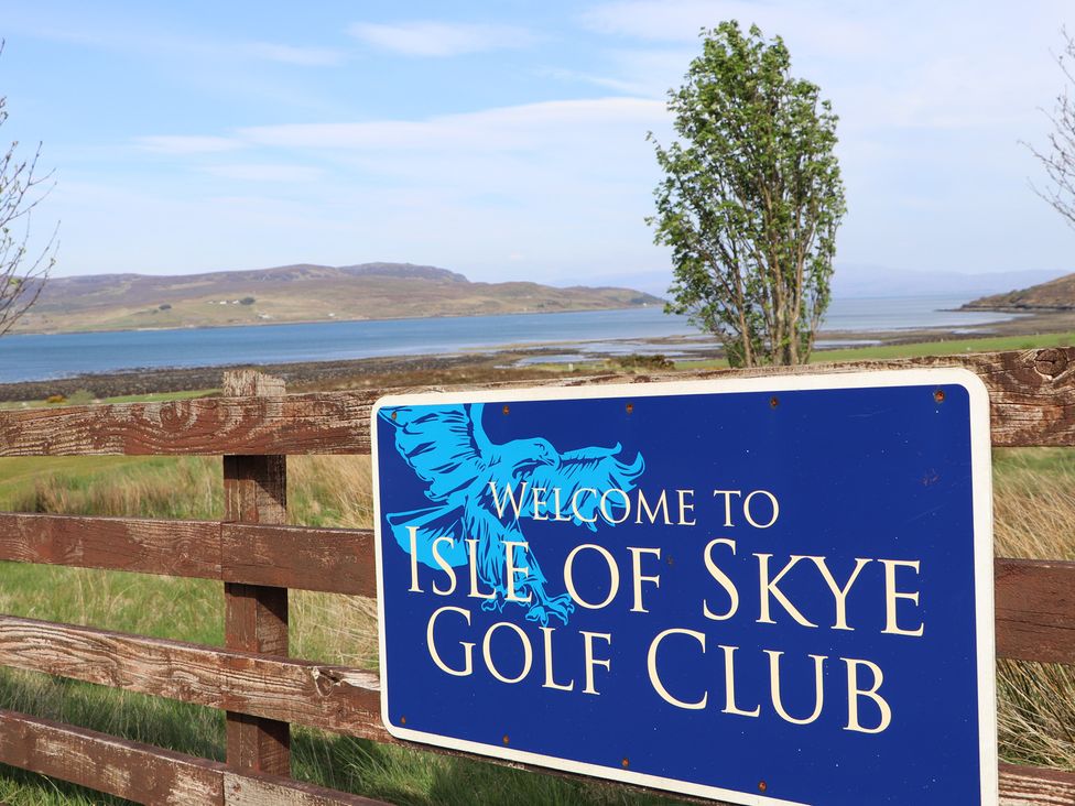A welcome sign for Isle of Skye Golf Club with a scenic background at MacKenzie’s Peak in Sconser near Portree