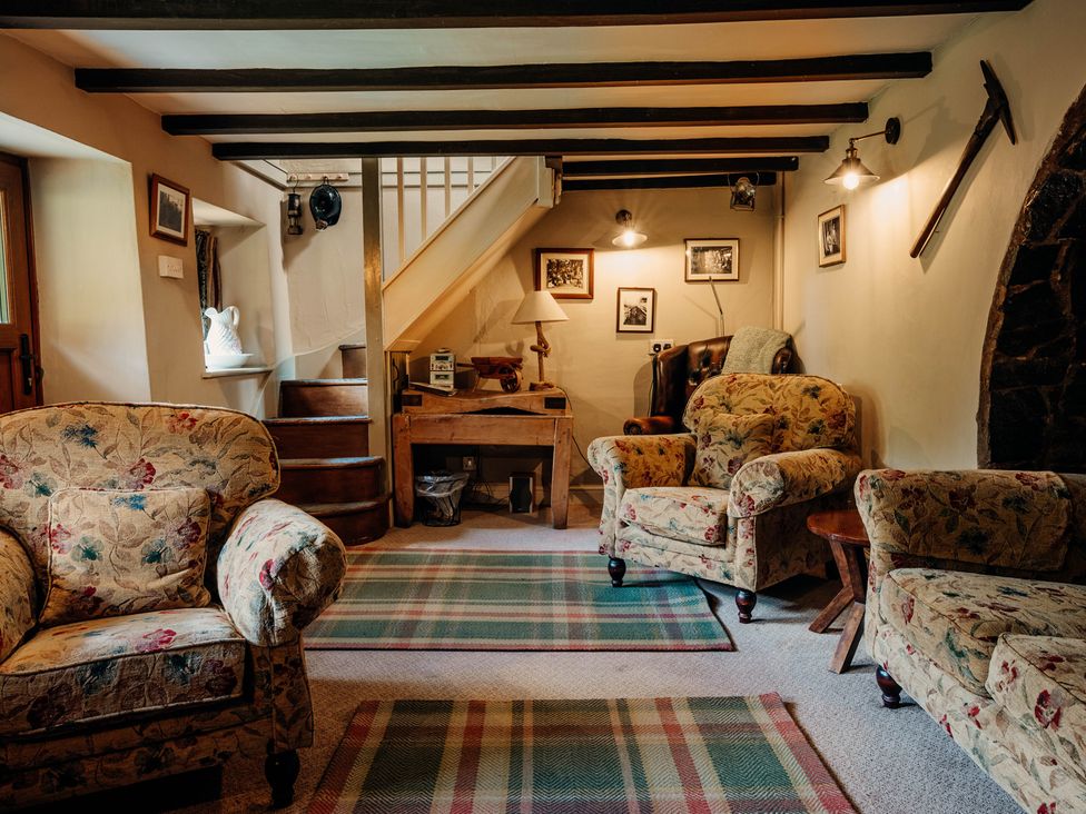 A snug with floral sofas and a staircase at The Wilderness in Stiperstones