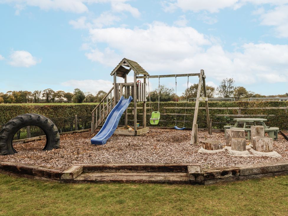 A playground with a slide, swings, and a picnic table at Pear Tree Cottage in Dunnington