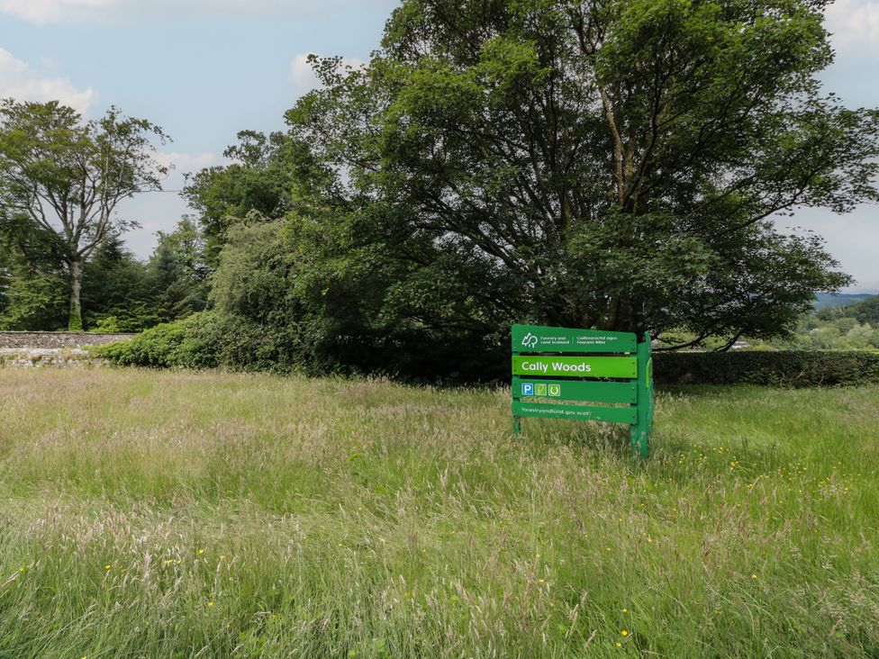 A sign for Cally Woods with trees and grass in Gatehouse of Fleet
