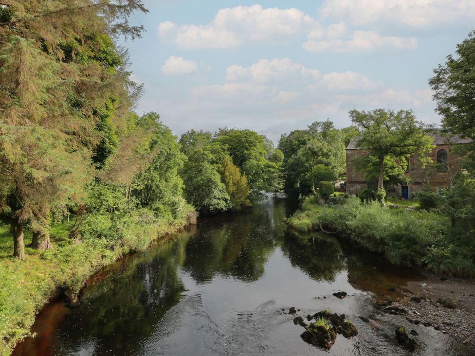 A river surrounded by trees with a building nearby at 79 Laurel Bank in Gatehouse of Fleet