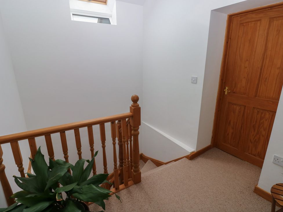 A staircase with wooden rail and door at Bwthyn-y-Rhiw in Penybanc near Llandeilo