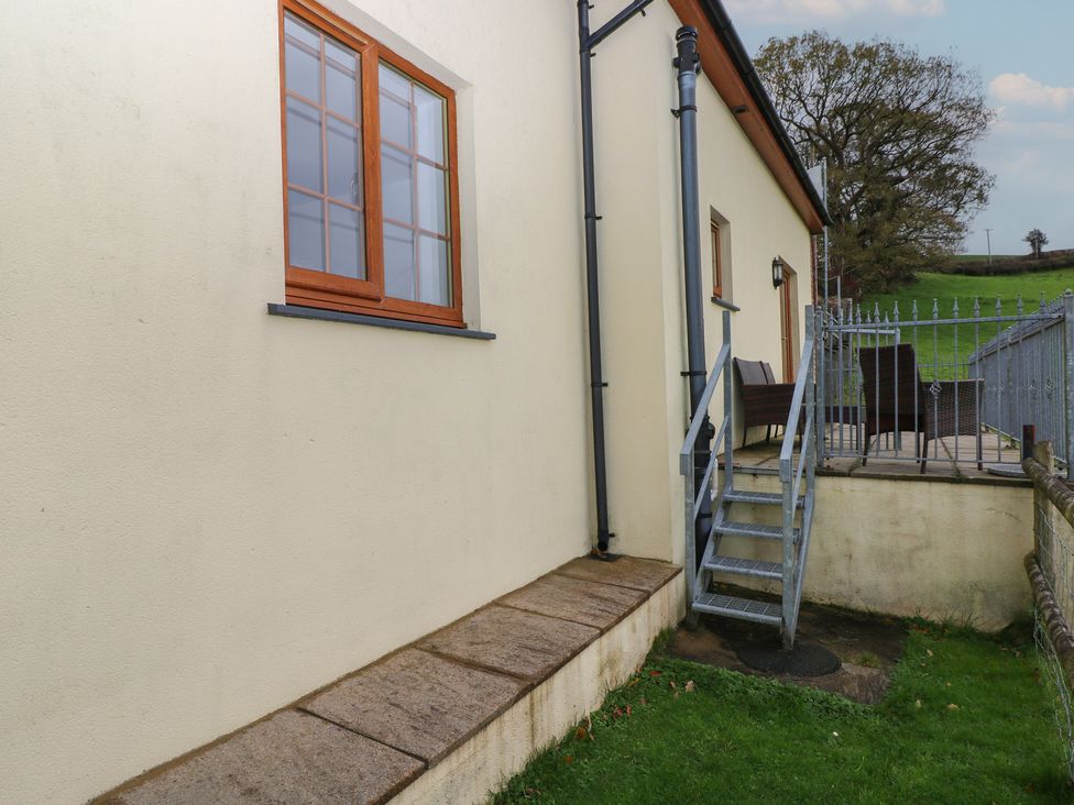 An exterior view showing a window and stairs leading to a patio at Bwthyn-y-Rhiw Penyban near Llandeilo