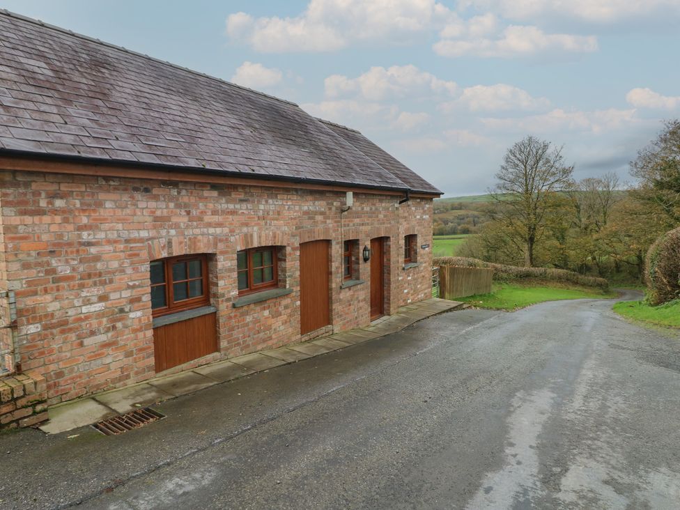 A brick building with wooden doors and windows near a road at Bwthyn-y-Rhiw Penybanc near Llandeilo