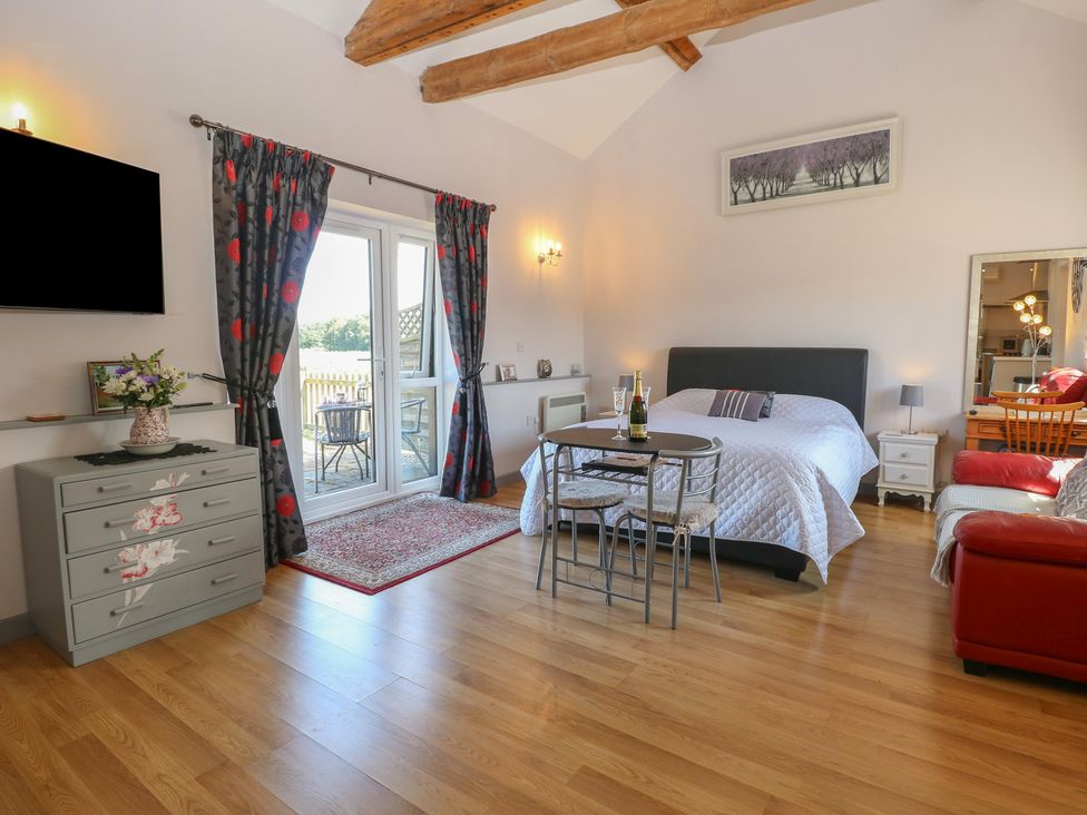 A bedroom with a bed and dining table at Snowy Owl Barn in Shipdham
