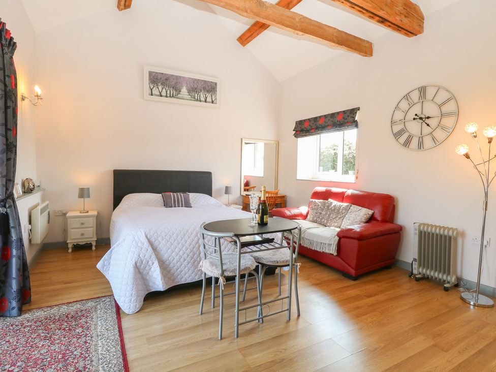 A bedroom with a bed, table, and sofa at Snowy Owl Barn in Shipdham