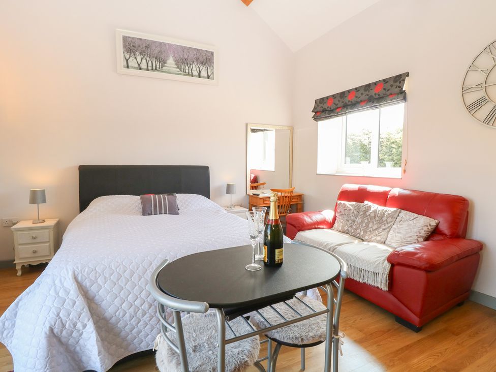 A bedroom with a bed and seating area at Snowy Owl Barn in Shipdham