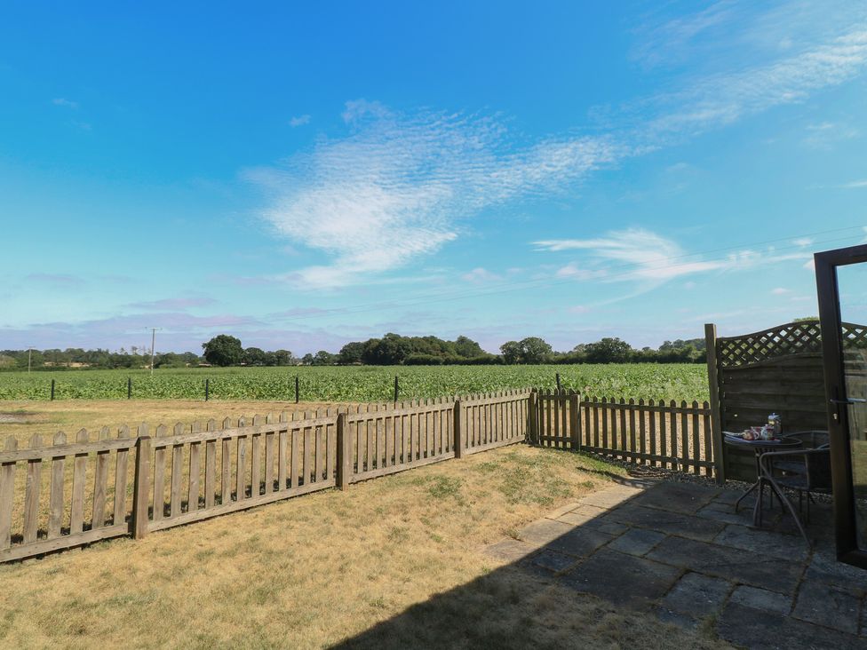 A garden with a fenced area and a table and chairs at Snowy Owl Barn in Shipdham