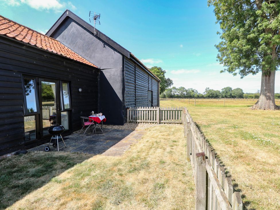 An outdoor area with a table and chairs near a house at Tawny Owl Barn Shipdham near Dereham