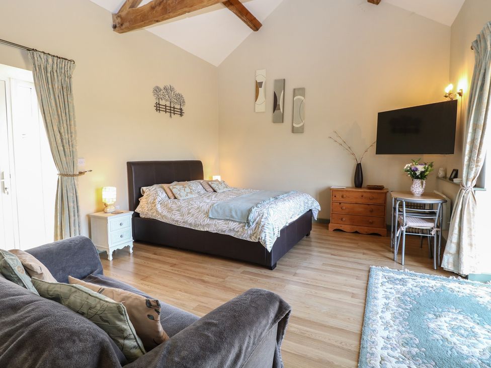 A bedroom with a bed, sofa, and television at Tawny Owl Barn in Shipdham near Dereham