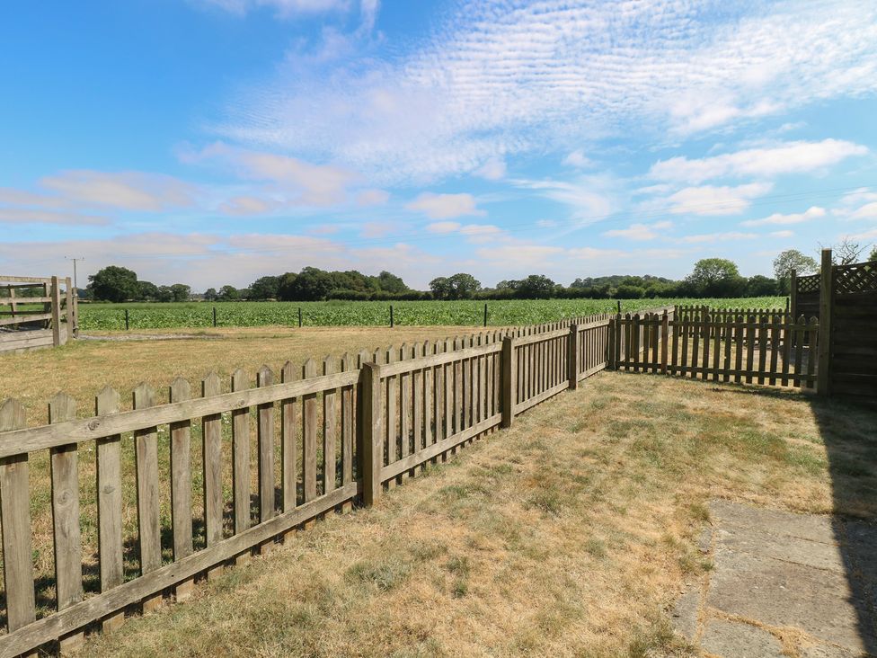 An outdoor area with a wooden fence and a view of a farm field at Tawny Owl Barn Shipdham near Dereham