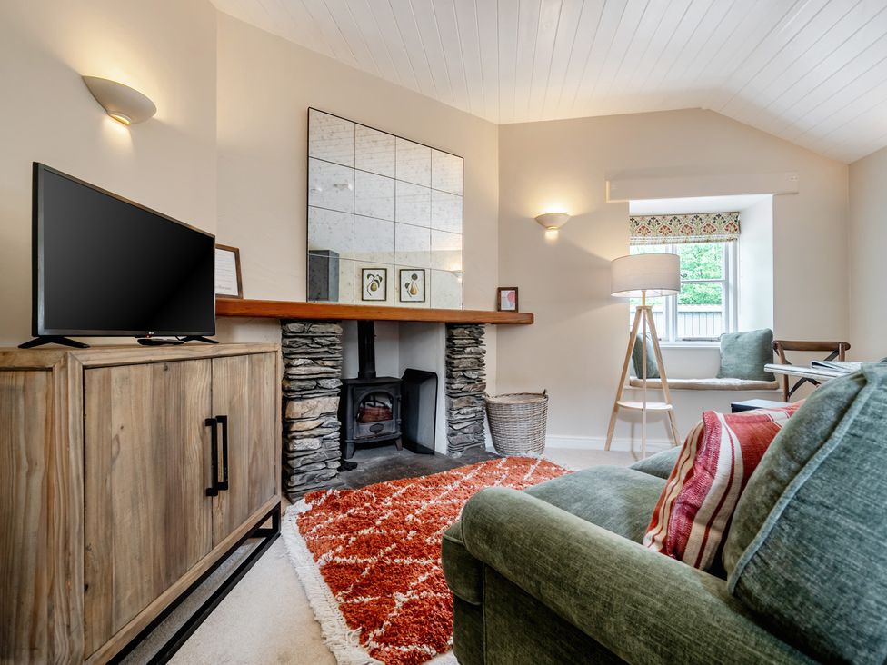 A living room with a television and stone fireplace at Can Brow at the Graythwaite Estate near Hawkshead