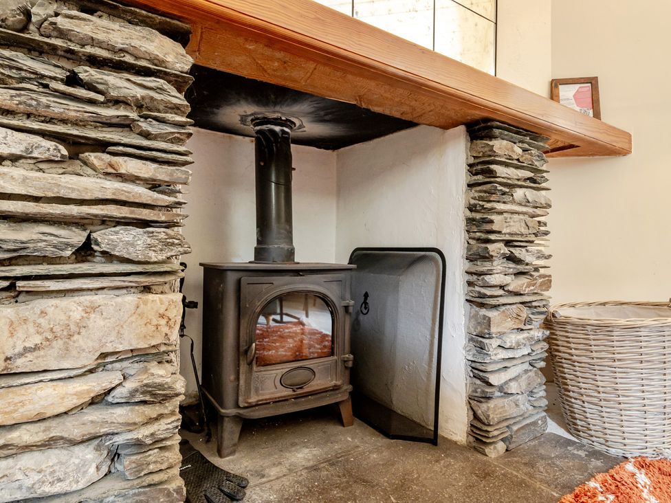 A living room with a wood stove and stone surround at Can Brow at the Graythwaite Estate near Hawkshead