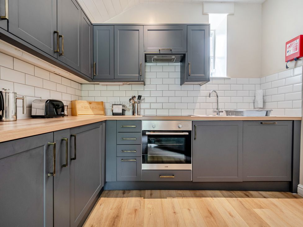 A kitchen with cabinets, an oven, and a sink at Can Brow at the Graythwaite Estate near Hawkshead