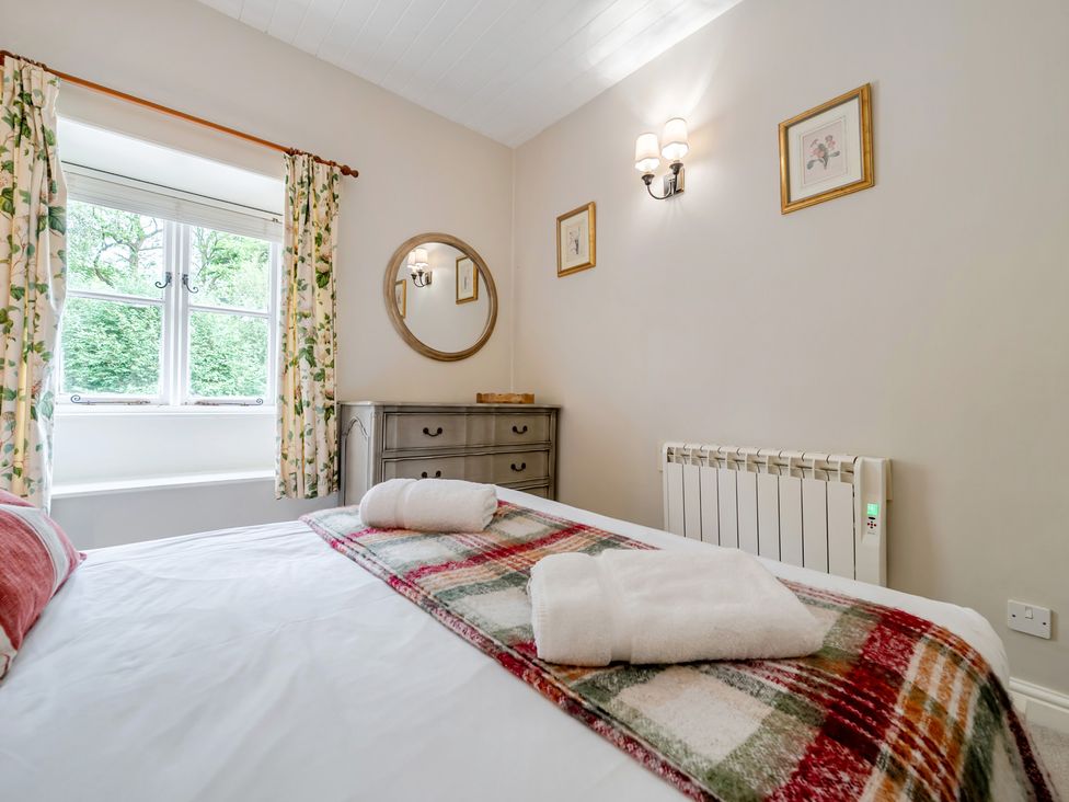 A bedroom with a bed and dresser at Can Brow at the Graythwaite Estate near Hawkshead