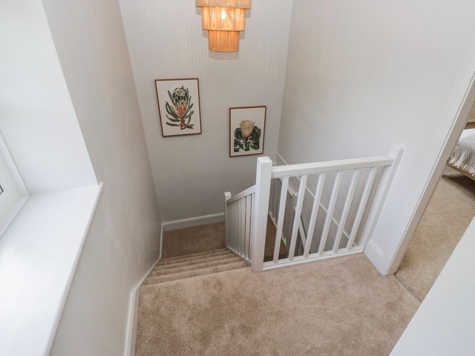 A staircase with wall decor and a chandelier at Jubilee in Graythwaite near Hawkshead