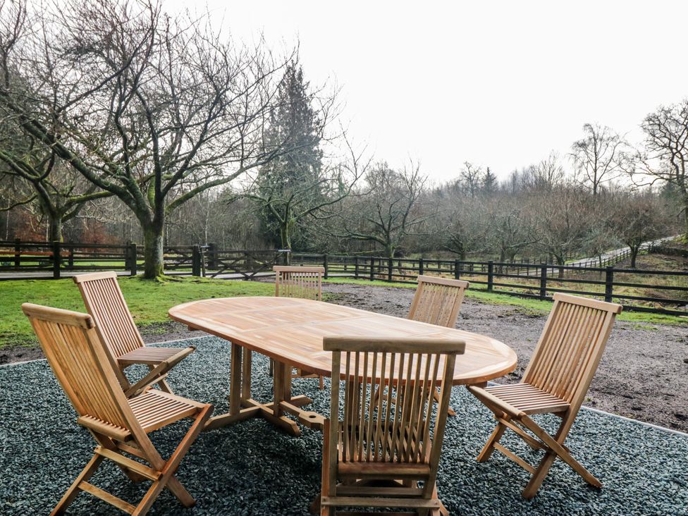 A garden with a wooden table and chairs at Jubilee in Graythwaite near Hawkshead