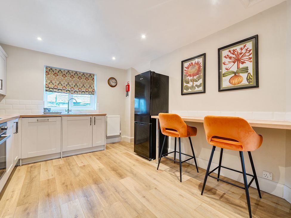 A kitchen with a refrigerator and bar stools at Jubilee at the Graythwaite Estate Graythwaite near Hawkshead
