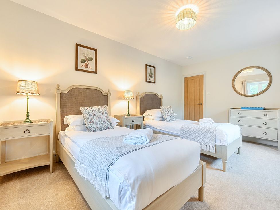 A bedroom with two beds and a chest of drawers at Jubilee at the Graythwaite Estate Graythwaite near Hawkshead