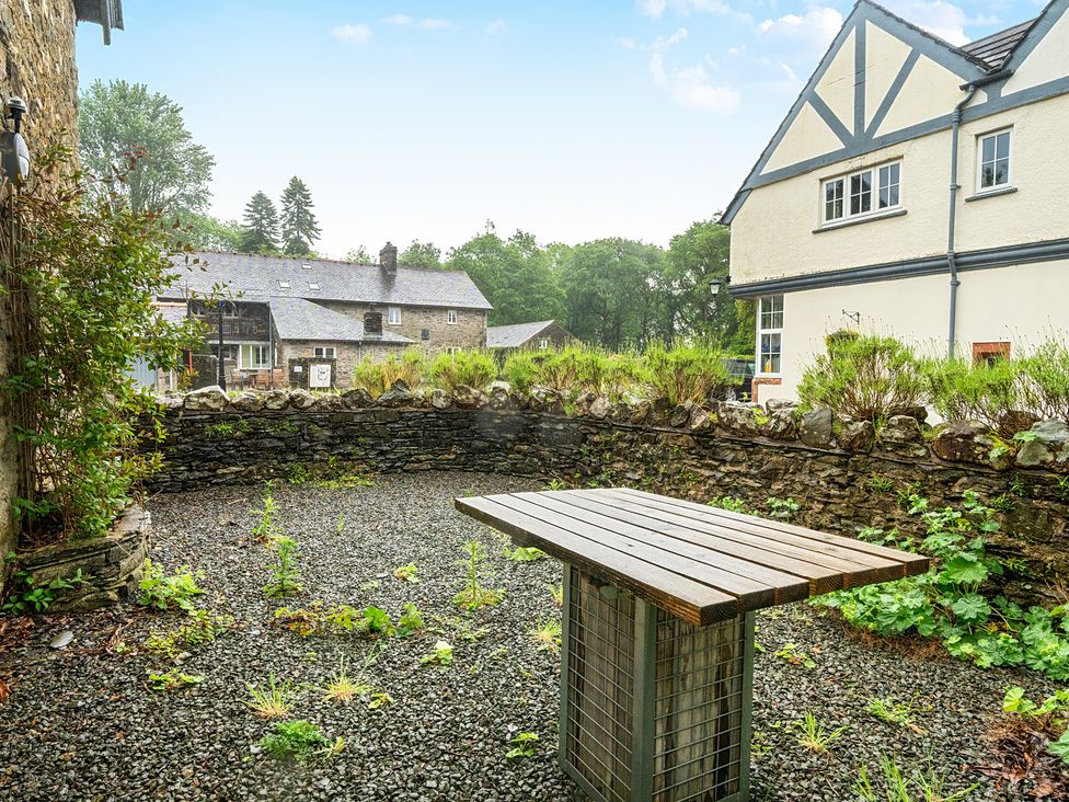 A garden with a wooden table and stone wall at Jubilee at the Graythwaite Estate Graythwaite near Hawkshead