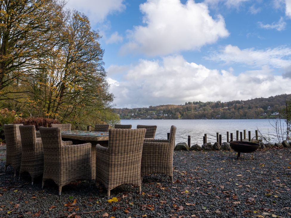 An outdoor area with a table and chairs by a lake at Hammerhole Graythwaite near Hawkshead