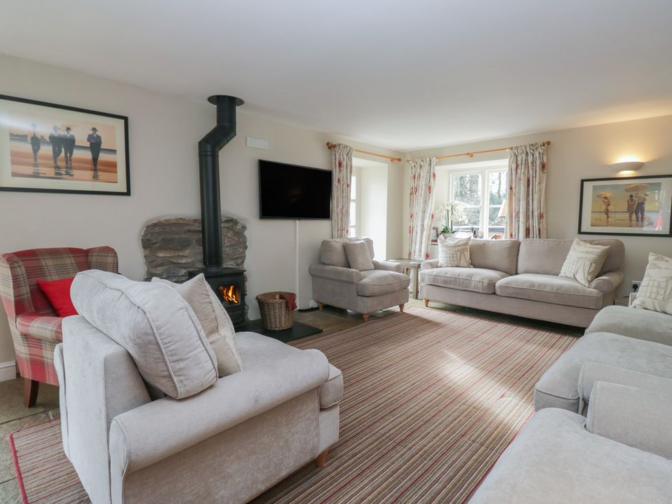 A living room with sofas, an armchair, and a fireplace at Hammerhole in Graythwaite near Hawkshead