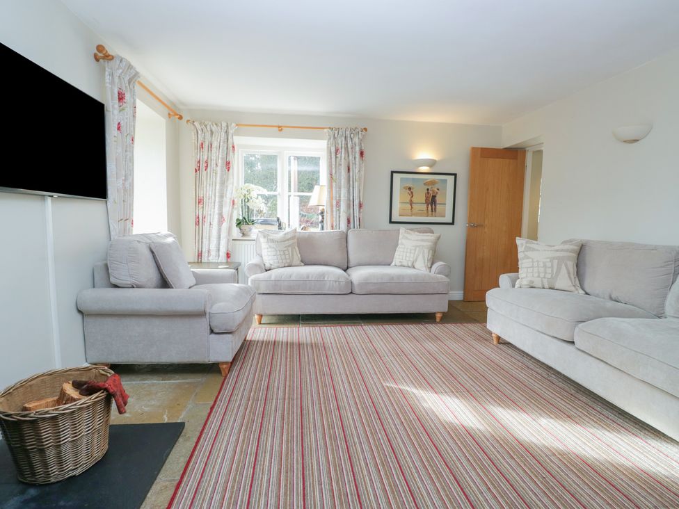 A living room with a sofa, armchair, and television at Hammerhole in Graythwaite near Hawkshead