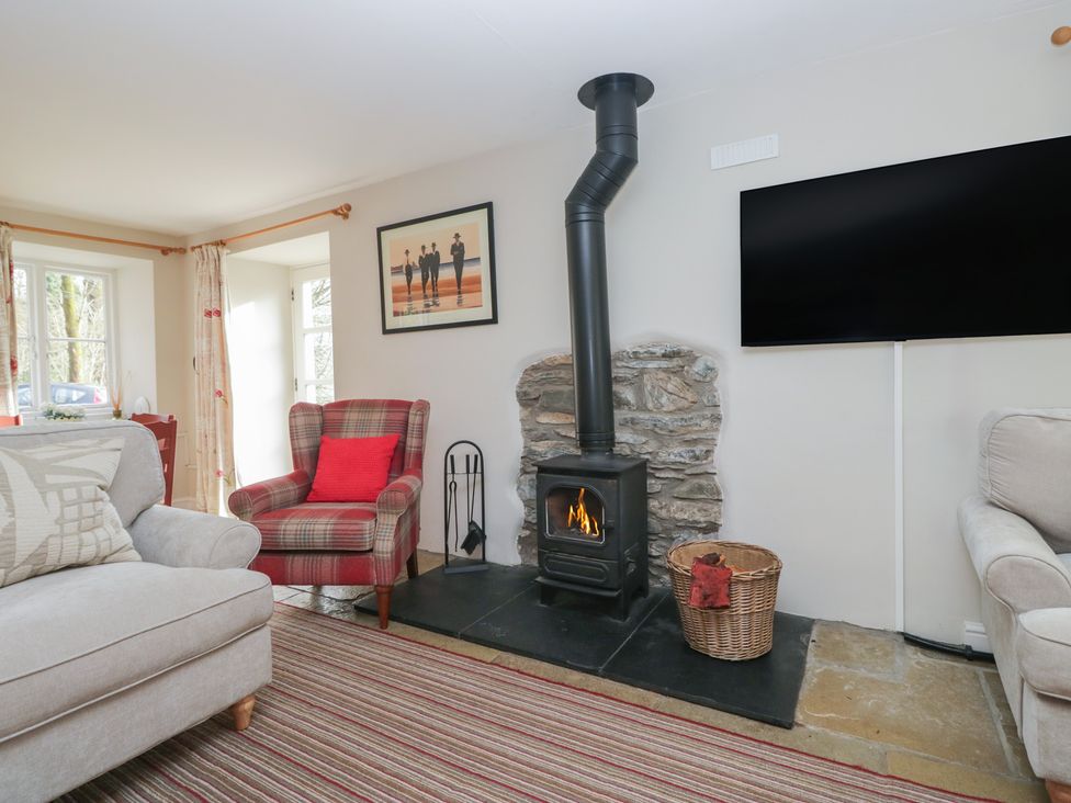 A living room with a wood stove and armchair at Hammerhole in Graythwaite near Hawkshead