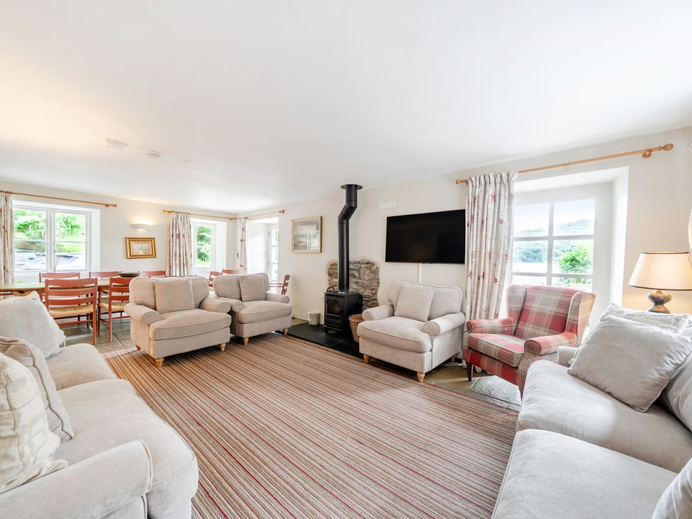 A living room with sofas, armchair, and dining area at Hammerhole at the Graythwaite Estate near Hawkshead