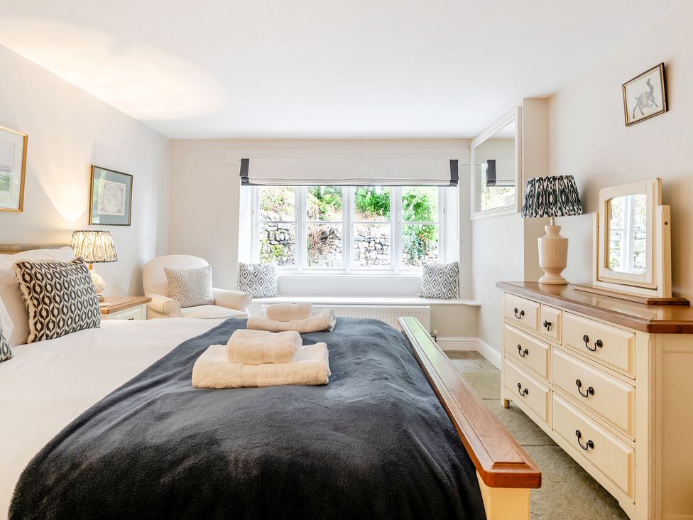 A bedroom with a bed, dresser, and armchair at Hammerhole at the Graythwaite Estate near Hawkshead