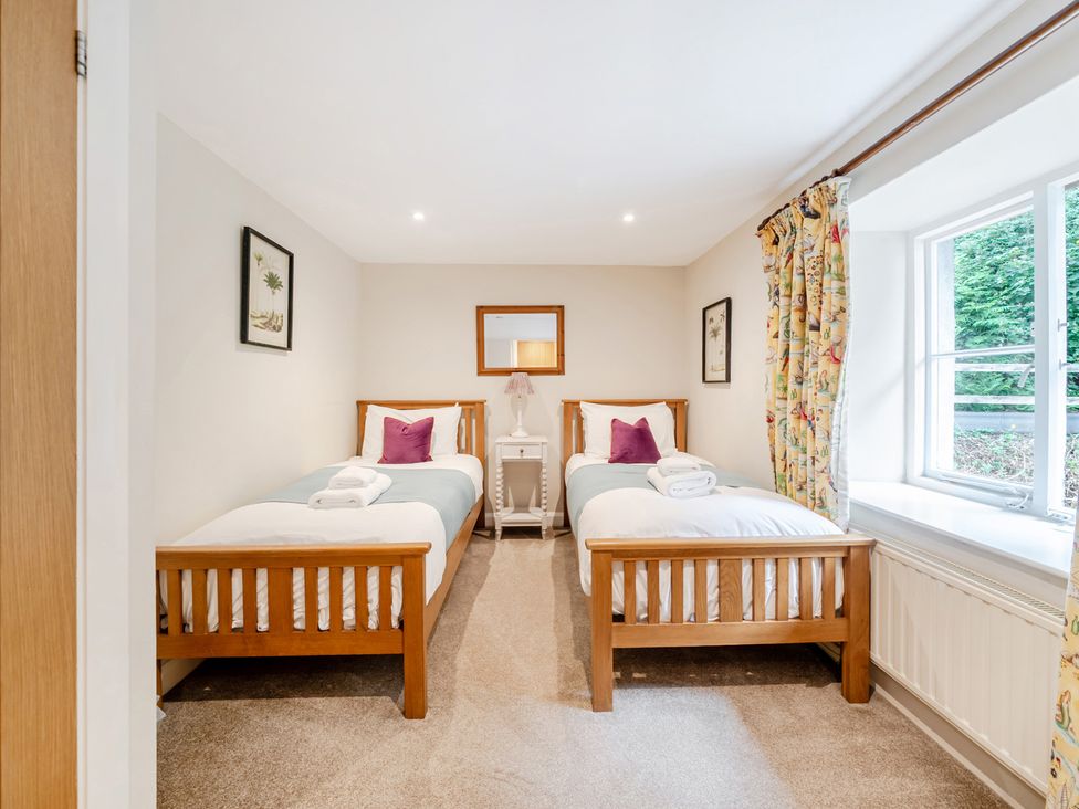 A bedroom with two beds and a nightstand at Hammerhole at the Graythwaite Estate near Hawkshead