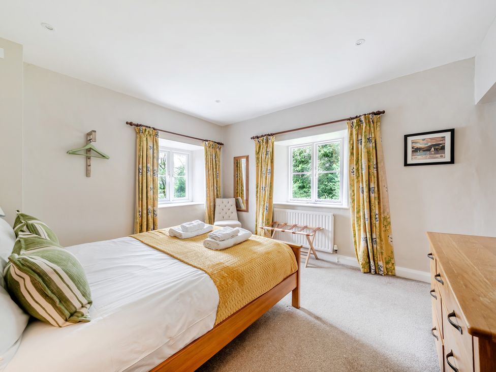 A bedroom with a bed and windows at Hammerhole at the Graythwaite Estate near Hawkshead